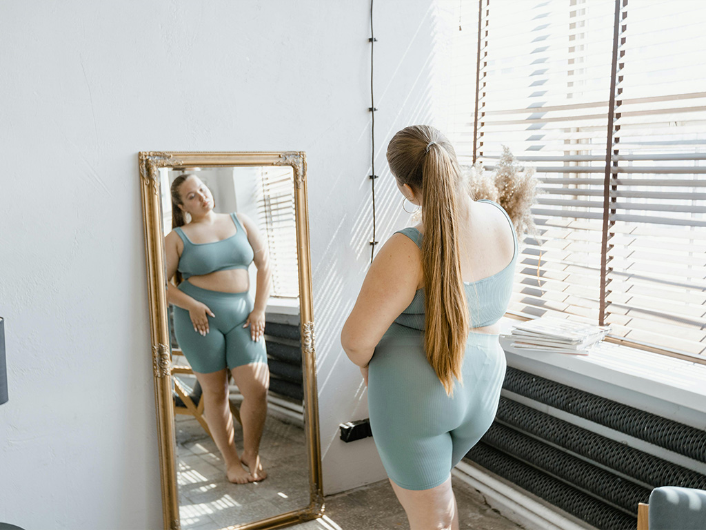 Woman Looking in Mirror Plus size woman looking at herself in the mirror unhappy, Ness healthcare